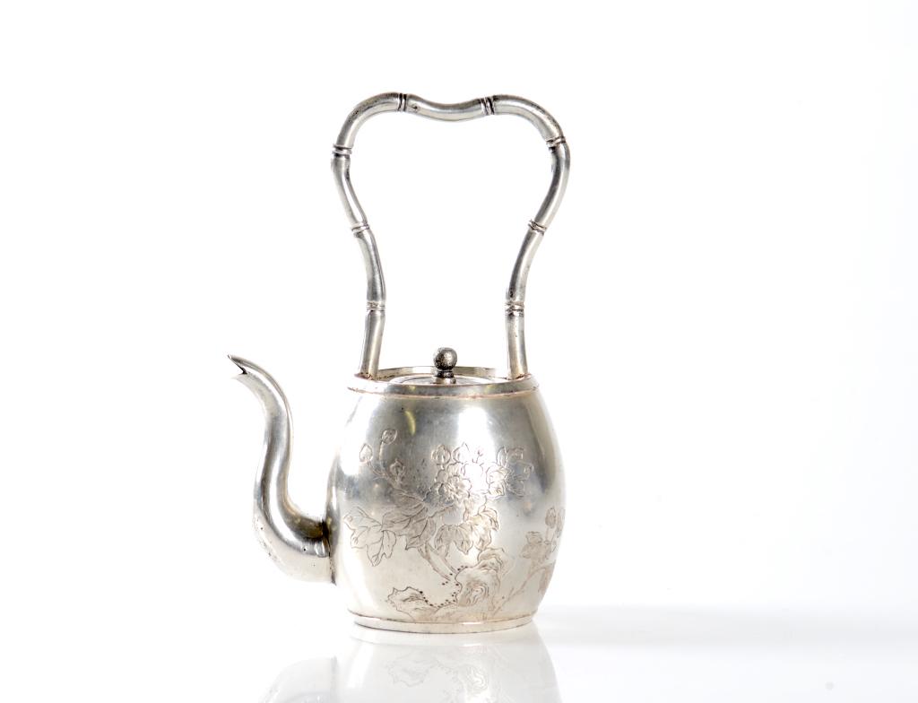 CHINESE SILVER HANDLED TEAPOT: Decorated with floral pattern to body, long upright bamboo form handle to top. Marked Guangzhou Shi & Meng Ji Shi to base. H: 15.2cm (6 in.) Weight: 190g. Condition report available upon request.