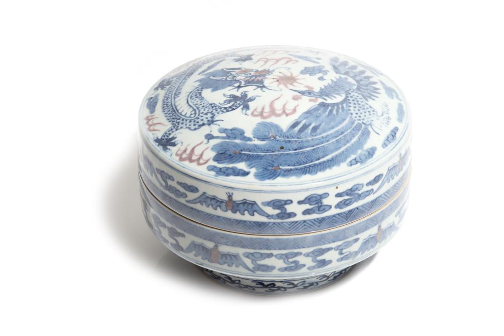 CHINESE COPPER RED, BLUE & WHITE PORCELAIN BOX: Painted with a dragon and phoenix to cover, bats and cloud to side. Six character apocryphal Chenghua mark to base. Dia. 21.5cm (8 1/2 in.) H. 15cm (6 in.) Condition report available uponrequest.