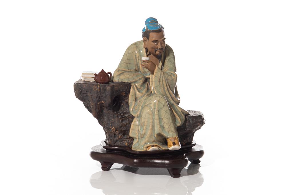 CHINESE SHIWAN POTTERY LI BAI FIGURE: The poet figure seated on a rock formation drinking tea or wine, cloth glazed in crackled celadon green. Impressed seal mark Liu Bing to interior. With fitted wood stand. Height on stand: 30.5cm (12 i