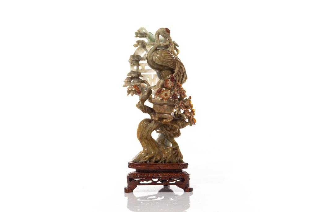 CHINESE JADEITE CARVED CRANE GROUP: Overall carved with a crane perched on a flowering tree against a circular stylized shou symbol. With fitted wood stand. Overall height on stand: 26cm (10 1/4 in.) Condition report available uponreque
