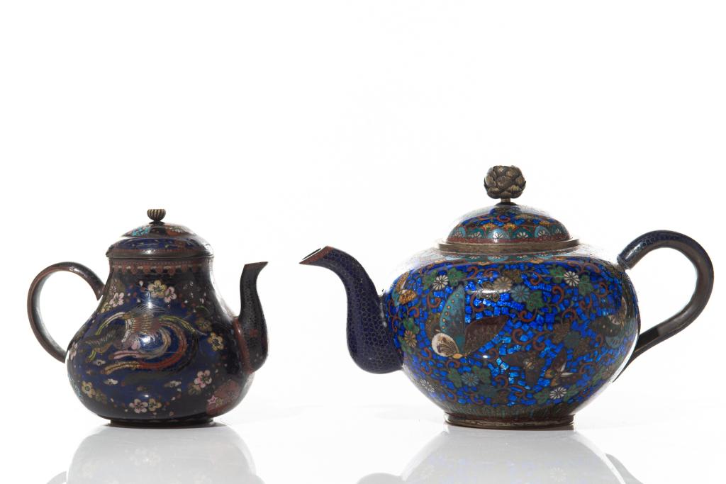 TWO JAPANESE CLOISONNE ENAMELLED TEAPOTS: Larger teapot of a cobalt blue tone, decorated with butterfly and floral detail. Smaller teapot with red sparkle and yellow dragon detail. Meiji era (19th C. to early 20th C.) Height of largeteapot:14