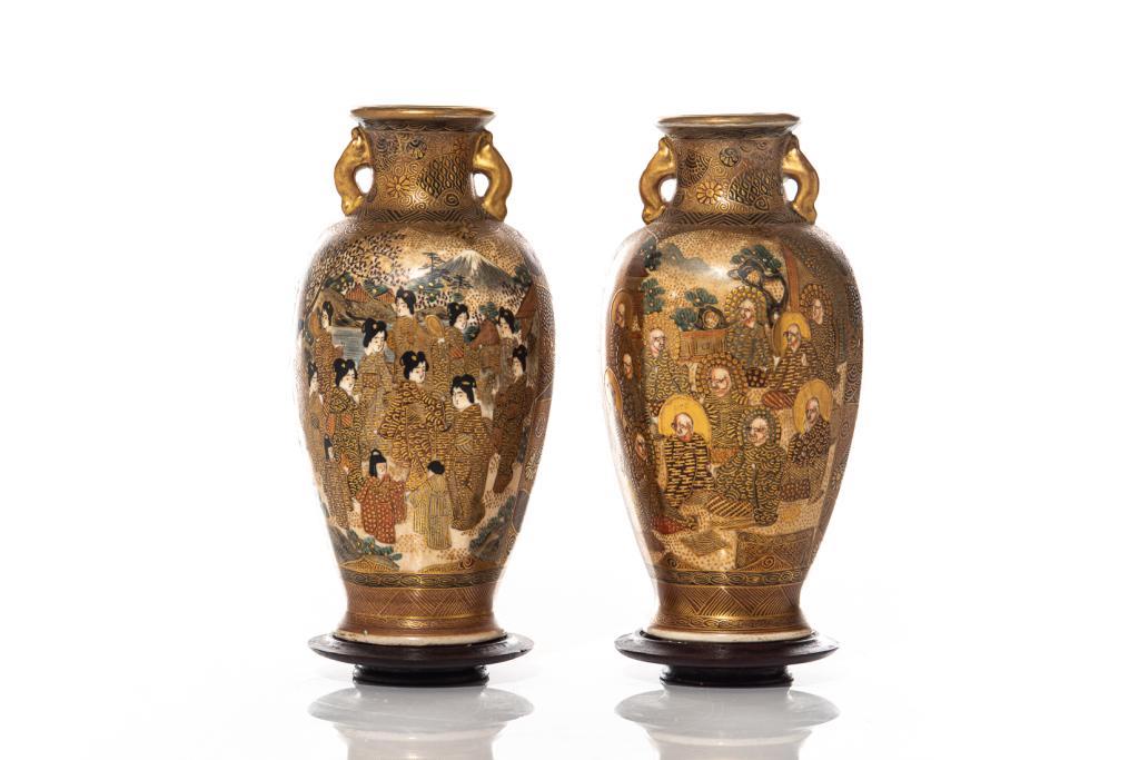 PAIR OF JAPANESE SATSUMA VASES: Meiji era (1868-1912). Two vases painted with faces of women on one side and men on the other. Scenes of nature in the background. Fixed to wood stand. H: 16 cm (6.3 inch.) Condition reportavailable u