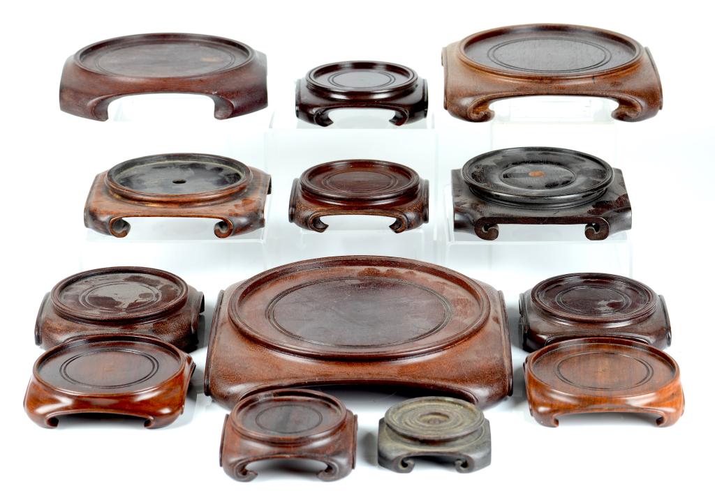 THIRTEEN CHINESE CARVED HARDWOOD STANDS: Squared base for circular vases with carved rolled ogee feet, some pairs noted early to mid 20th C. Inset of smallest 6cm (2 1/4in) largest 19cm (7 1/2in)