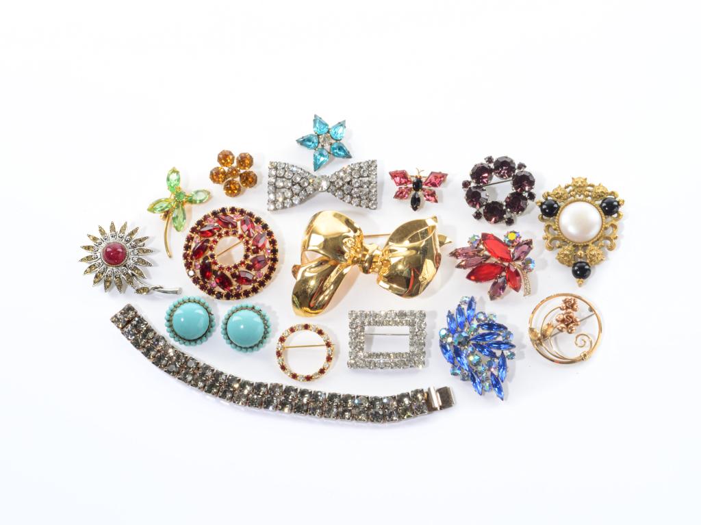 LOT OF VINTAGE RHINESTONE BROOCHES: Including brooches in the shape of flowers, one in the shape of a barrette, and bowties. Together with a gold-coloured big bow brooch, rhinestone double-chained bracelet and turquoise cufflinks.