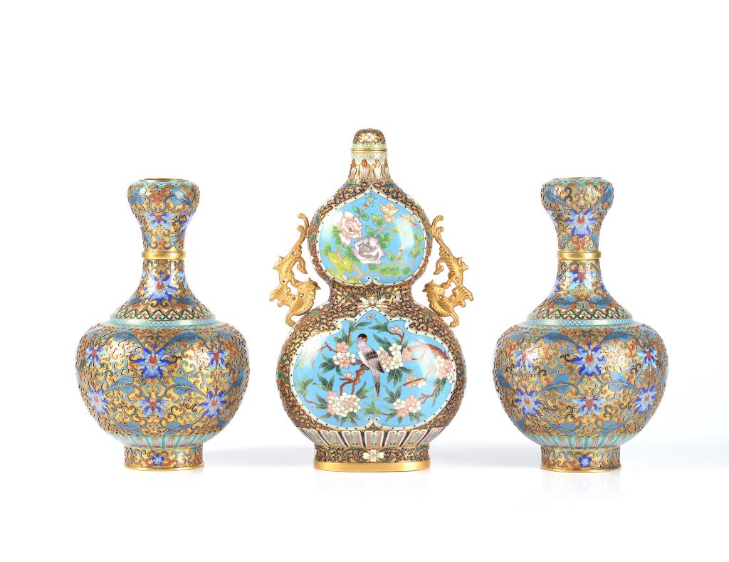 THREE PIECE CHINESE CHAMPLEVE ENAMELLED GARNITURE: Including a double gourd vase decorated with birds and flower scenes with a pair of gilt phoenix handles. A pair of garlic mouth vases decorated with lotus scrolls. Height of gourd vase: 31cm (12 in.)