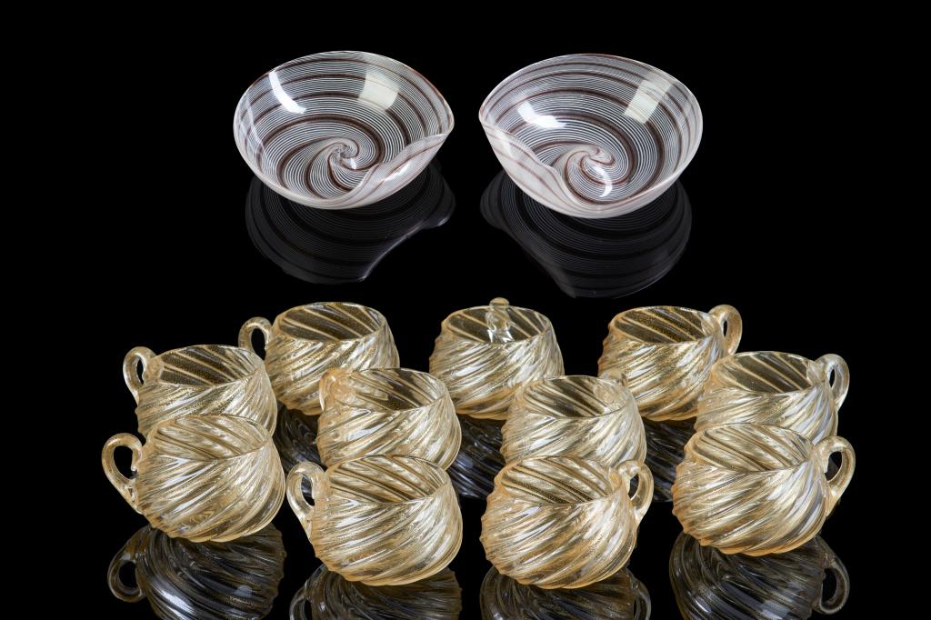 SET OF TEN MURANO TEA GLASSES AND PAIR OF BOWLS: 12 pieces included in total. Tea glasses are vintage with swirled body and gold flecked inclusions. Pair of owls feature red, gold and white striation design and irregular shape. Diameter at largest p