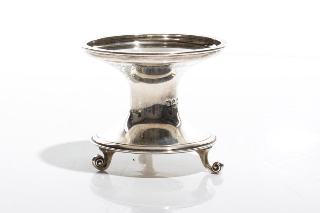 1911 ENGLISH SILVER COMMEMORATIVE SALT, 172g: A waisted form salt dish raised on three scroll feet. Underside inscribed GEORGE V and 1911. The inscription along the upper rim reads, "This Replica of an Ancient Salt was presented to Edward Hipwell