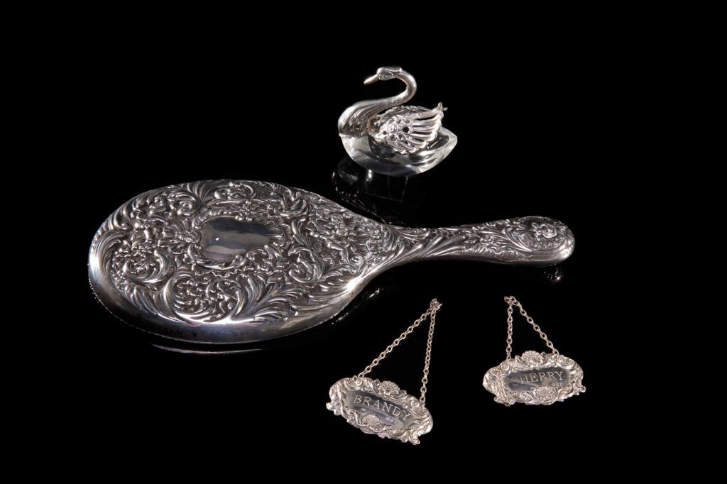 GROUP OF ASSORTED SILVER ACCESSORIES: Group is comprised of four items including English hand mirror, two decanter labels & German swan master salt dish with glass body. Mirror marked with hallmarks for London 1899, maker "GD". Brandy & S