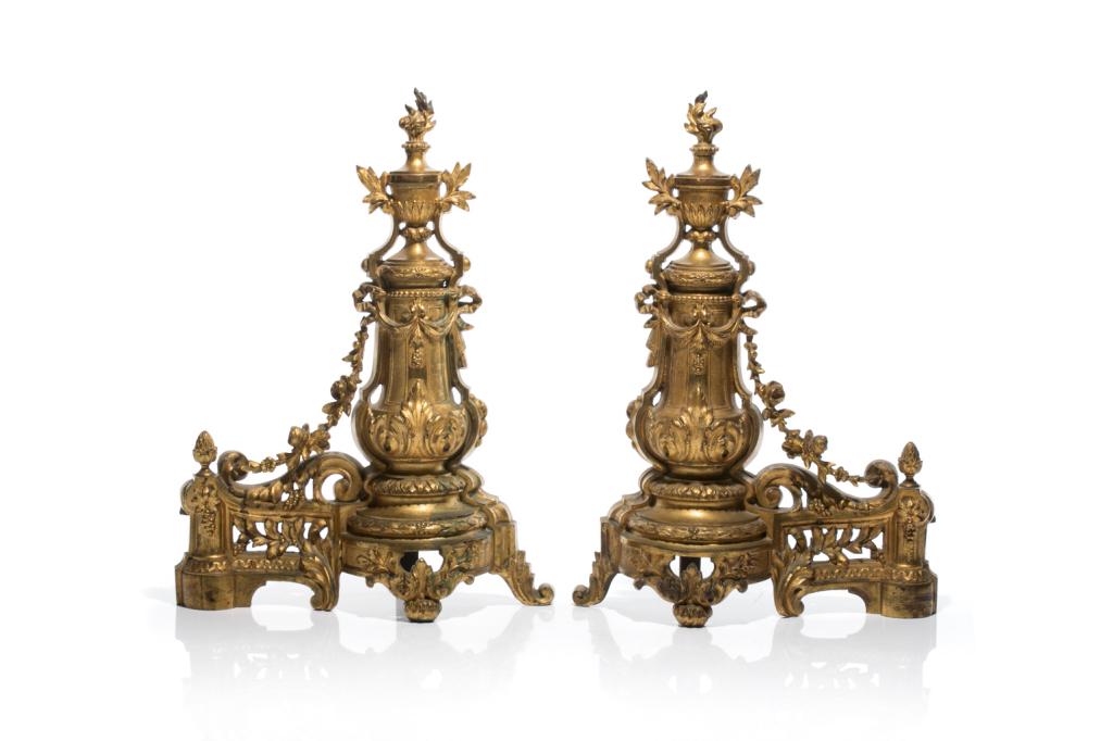 PAIR OF FRENCH GILDED BRONZE ANDIRONS: 19th century, with foliate motifs and floral swags. Raised on pedestals with urn forms and flame. H. of each 45.5 cm (18 in) W. of each 33 cm (13 in)