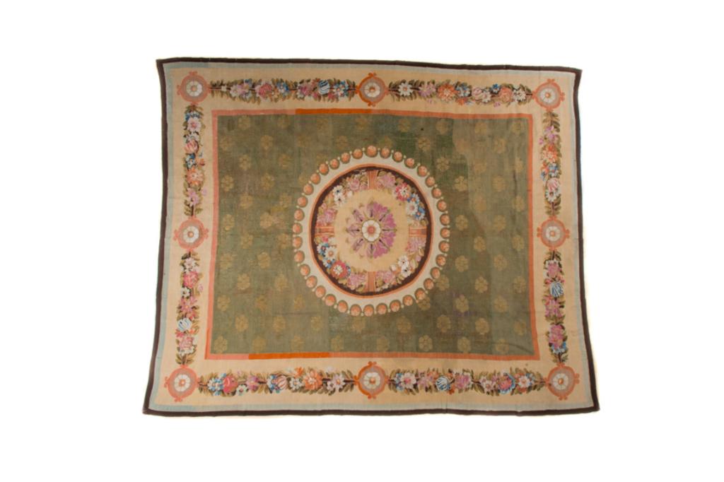 HAND KNOTTED FLAT WOVEN CARPET: Of European origins, in the manner of an aubusson with central green ground and foliate swag border. With medieval influences 10ft 6in x 8ft 6in