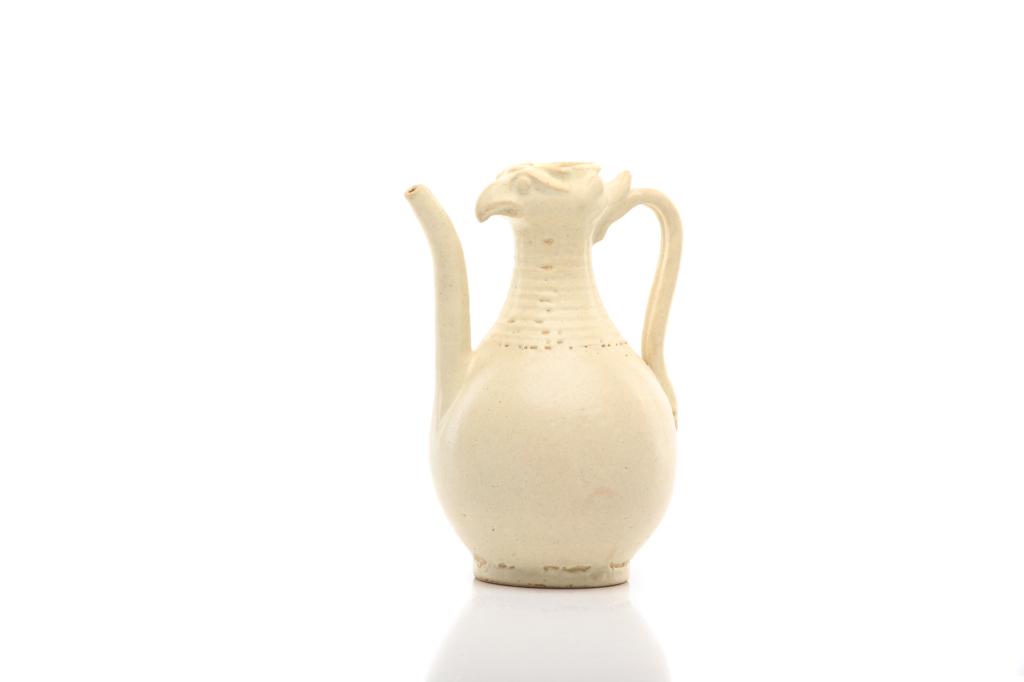 CHINESE WHITE GLAZED CHICKEN HEAD EWER: 白釉雞頭壺 Water-drop form body with ribbed neck and chicken head form top, affixed with a side strap handle and long outward flaring spout. H. 19.5cm (7 3/4 in.)