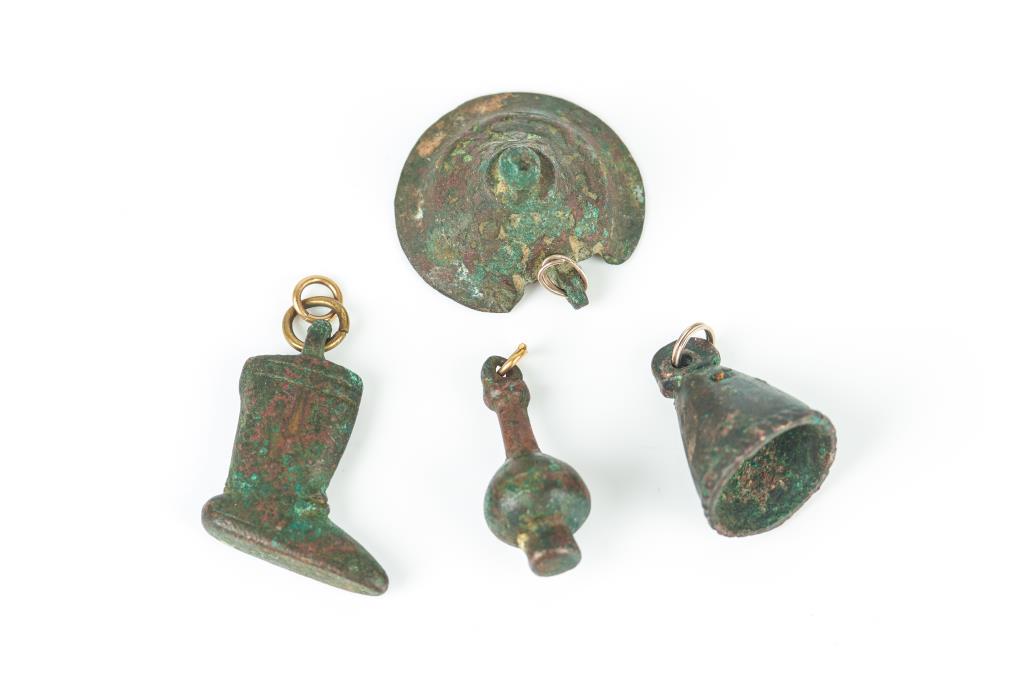 FOUR LURISTAN BRONZE AMULET PENDANTS: Of a bell, a boot, bottle and vessel top fragment, Southwest Persia, circa 1500 to 1000 BCE. H of boot 1in. Provenance: Three of the pendants with Phoenix Galleries