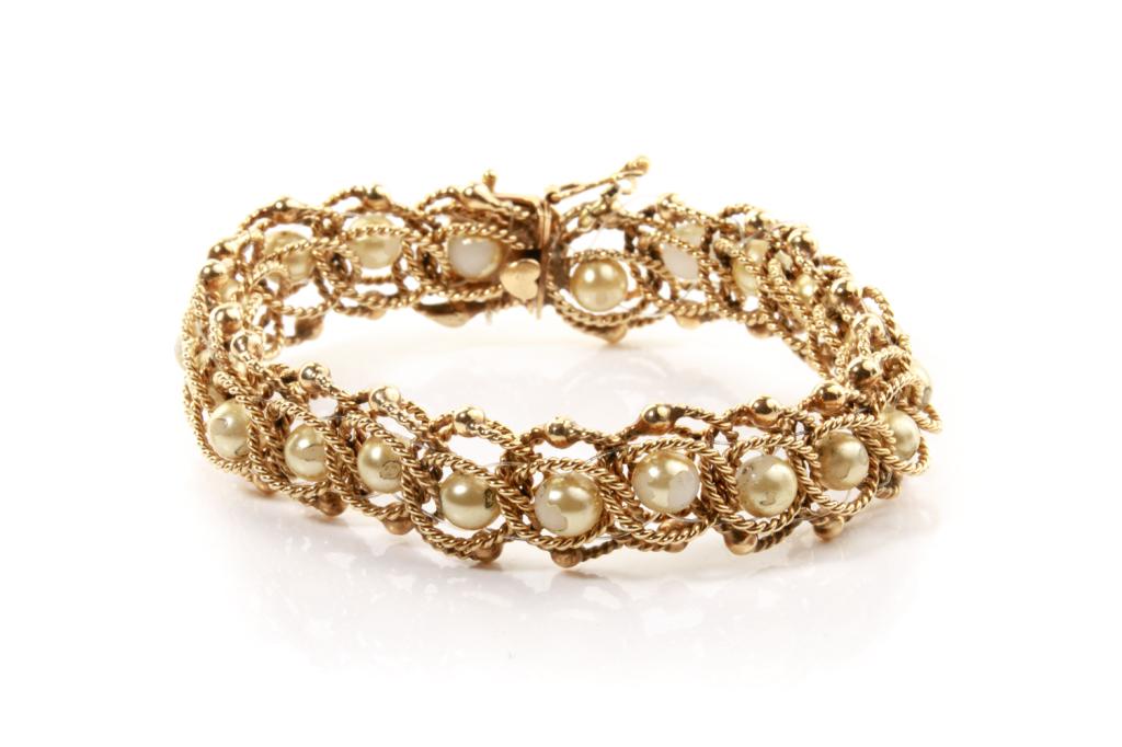 GOLD AND PEARL BRACELET, 44g: Yellow gold twisted wire link bracelet intertwined with pearl-like beads. Box closure with safety eight clasp. Testing 14k.