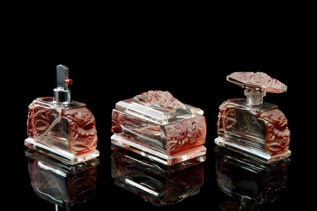 THREE CZECH ART DECO GLASS DRESSER SET: Clear glass with applied red stained stylized floral motifs around the sides and to the covers. Dresser box, scent bottle, and atomizer. H. of largest 12.5 cm (4 7/8 in)
