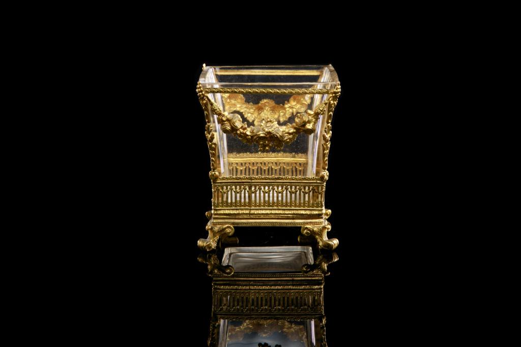 FRENCH GILT BRONZE & CUT GLASS CACHE POT: A square cut glass body with applied ormolu swags and decorative cartouches. Both cartouches with repousse depictions of (possibly) Venus and Cupid. Glass body raised on four gilt bronze acanthus leaf