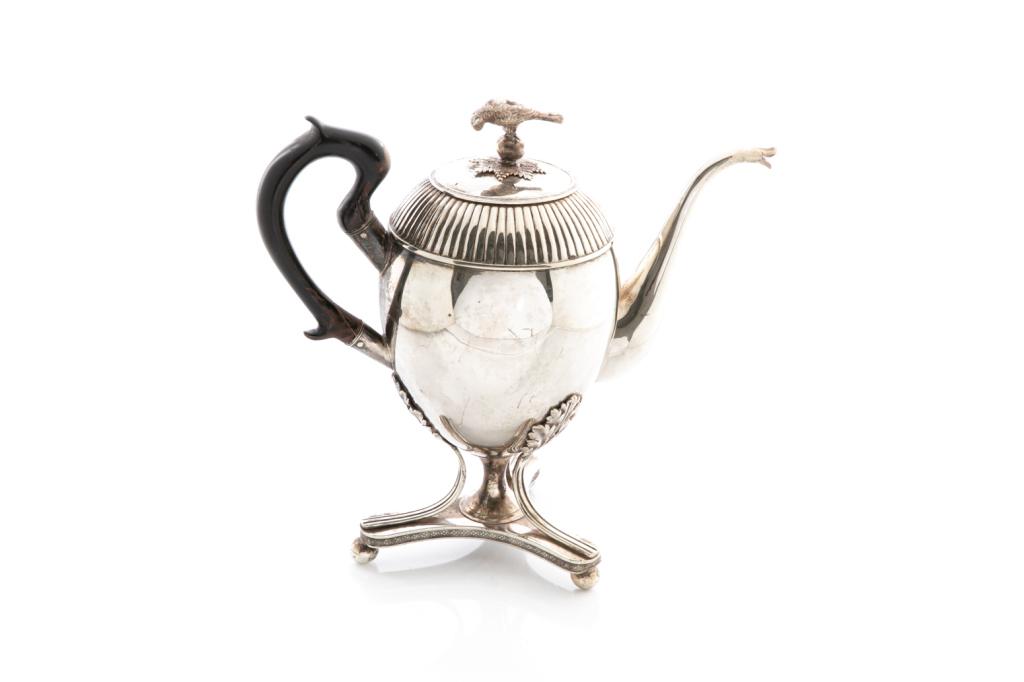SWEDISH EMPIRE SILVER COFFEE POT, 942g: Raised on a triangular base and ribbed detailing. Lid is detached and topped with a finial of a perched bird. Hallmarks to base, including date mark for 1835 and Carlsson (Johan Carlsson). H. to finia