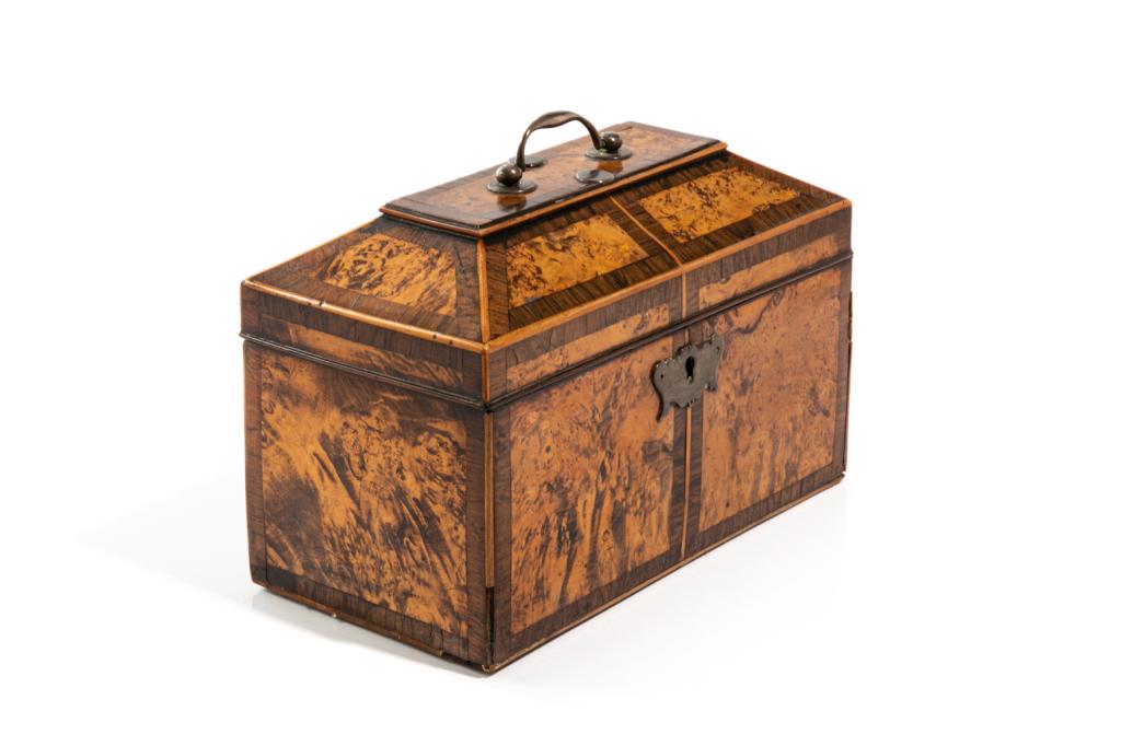 GEORGIAN BURLED WALNUT TEA CADDY: A rectangular body of burled walnut with zebrawood banding and hinged sloping lid topped with silvered metal handle and medallions to protect wood, and a silvered metal escutcheon to the front. Interi