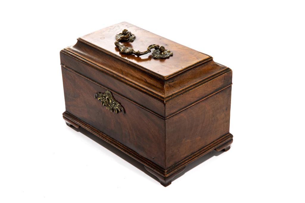 GEORGIAN MAHOGANY TEA CADDY: A rectangular box with hinged lid, topped with a brass pull handle and the front with a decorative brass escutcheon. English, c.1760. H. 16.4 cm (6 1/2 in.)L. 25 cm (9 7/8 in.)