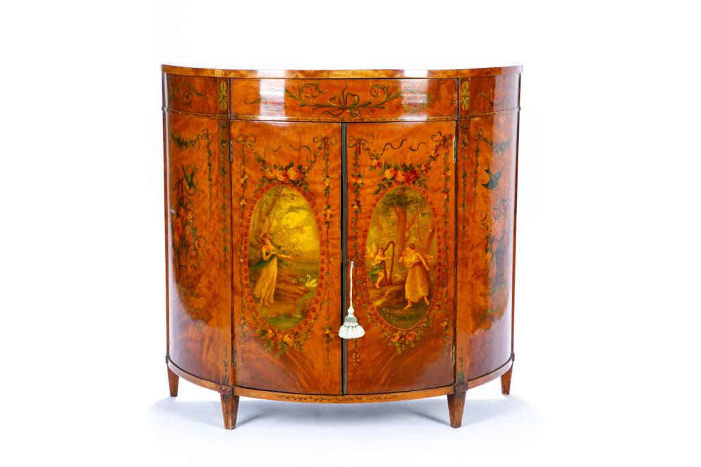 GEORGE III SATINWOOD DEMI LUNE CABINET: Finely painted Fragonard-style decoration over surface, including garlands of roses, blue bows, bluebirds and a mythological scene. Straight tapered legs, curved doors with lock and key. One drawer in