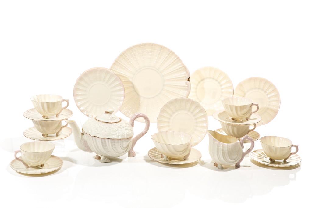 16 PCS BELLEEK FOOTED SHELL FORM PORCELAIN TEA SET: Irish, circa 1984 with iridescent and pink details, gilded trims. Group is comprised of a large serving dish, six cups & saucers, six small side plates, creamer, sugar and teapot with small shell fini