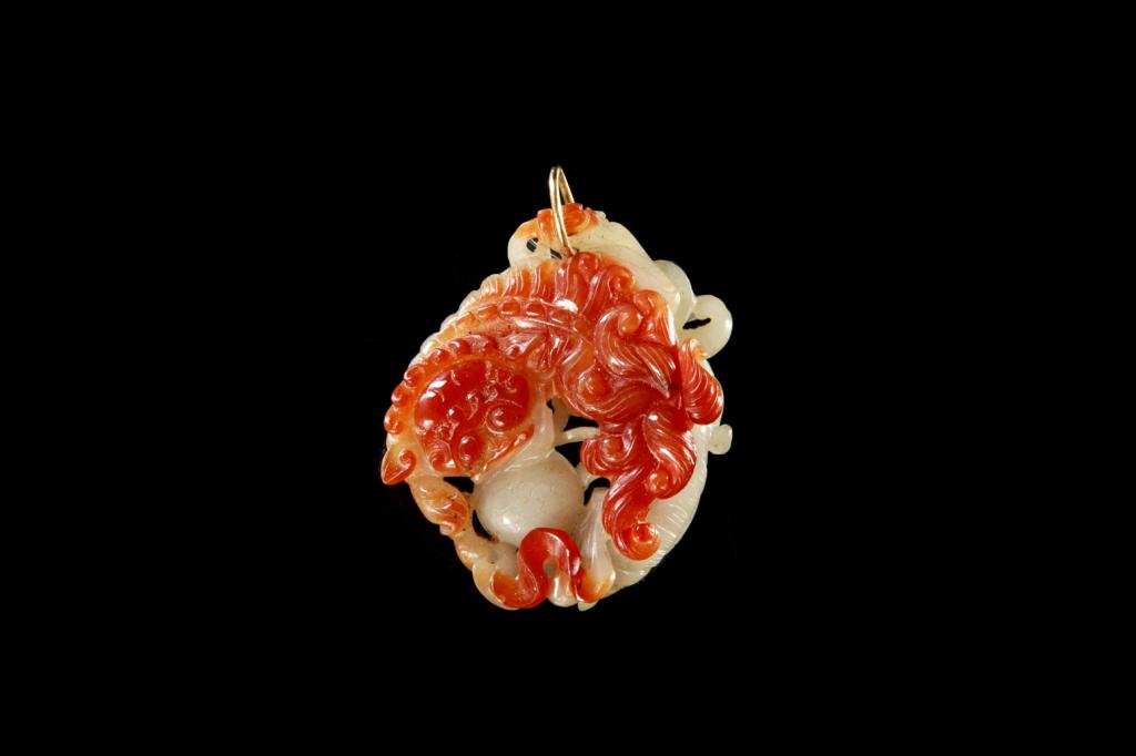CHINESE TWO TONED JADE LIONS PENDANT: The jade of a white and ruby red tone carved as two fu lions playing with a silk ball, one to each side of the plaque matching two distinct tone colors. 19th C. L. 5.7cm (2 1/4 in.)