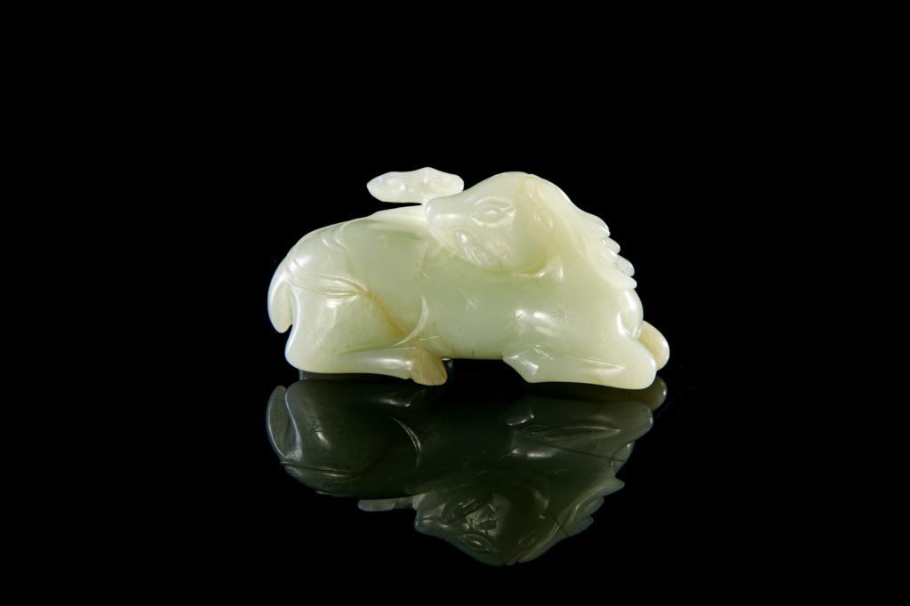 CHINESE MING JADE CARVED DEER AND LINGZHI: White to light celadon jade with slight russet inclusions. Carved as a resting deer with head turned and mouthing a lingzhi fungus. L. 8.3cm (3 1/4 in.)