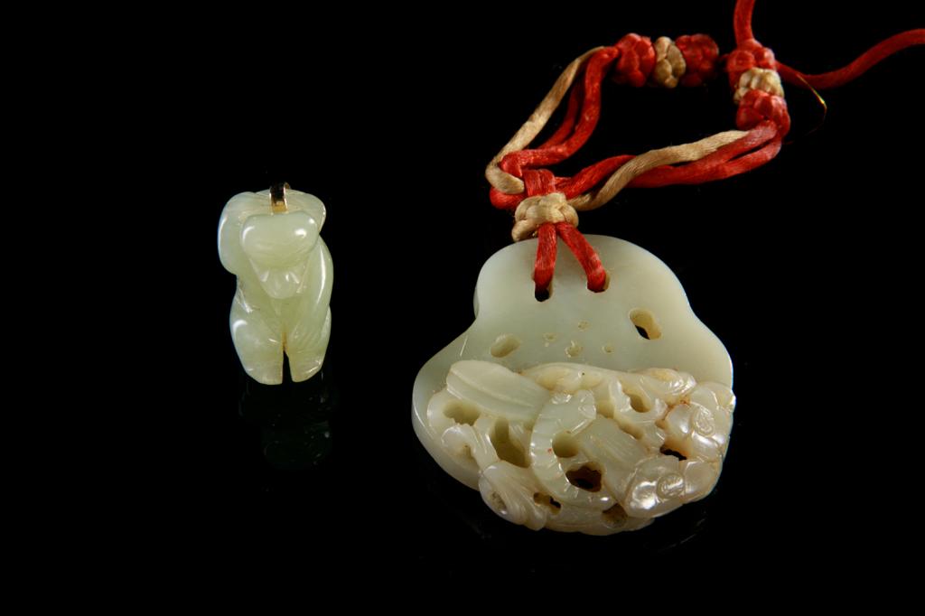 JADE CARVED LOTUS ROOT AND A JADE MONKEY: One carved as a pendant of lotus root with dragonfly and flowers, with silk string attachment. L. 6.5cm (2 1/2 in.) The other as a monkey figure. Qing dynasty. H. 3cm (2 1/8 in.)