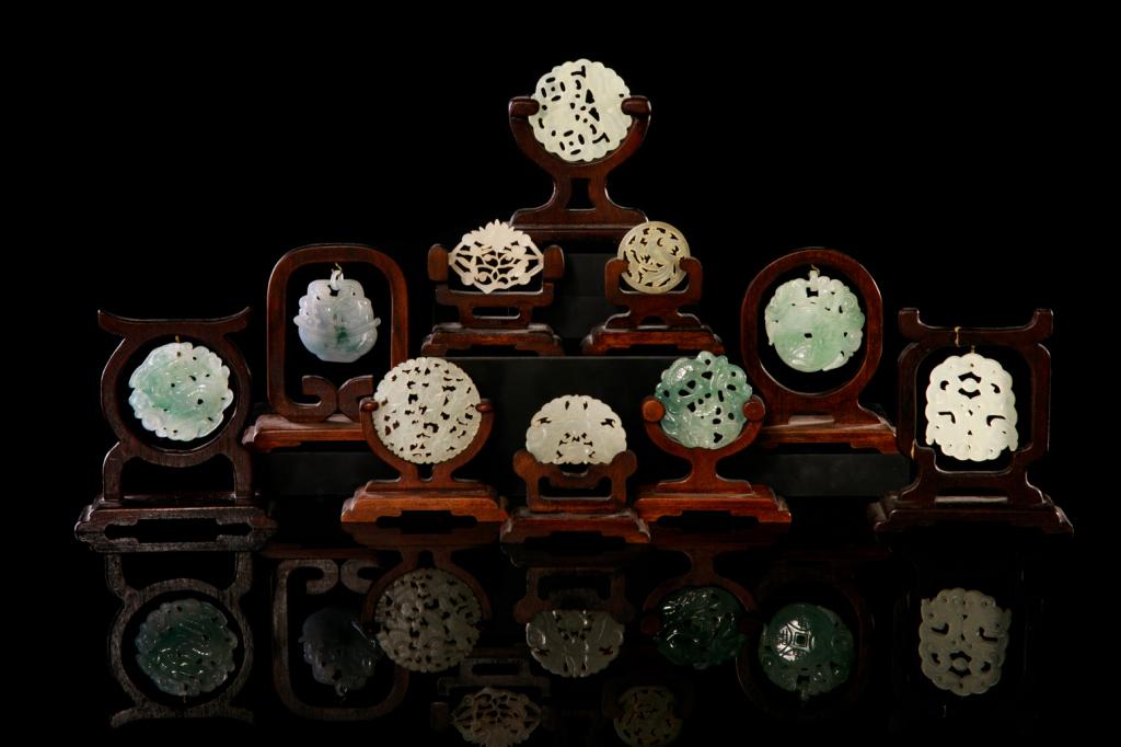 GROUP OF TEN JADE & JADEITE PLAQUES WITH STANDS: Including white jade and green jadeite, each carved with auspicious floral and animalmotifs. 19th to early 20th C. Largest plaque dia: 5.7cm (2 1/4 in.)