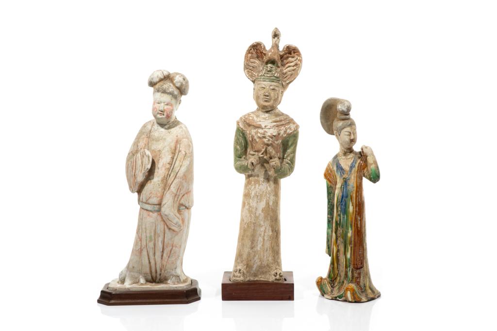 THREE TANG DYNASTY STYLE POTTERY FIGURES: One of a sancai glazed woman figure. The other two with polychrome painted decoration and fitted with wood stands. Tallest figure: 58cm (22 3/4 in.) Provenance: Collection of Mark and Suzanne Gayn.