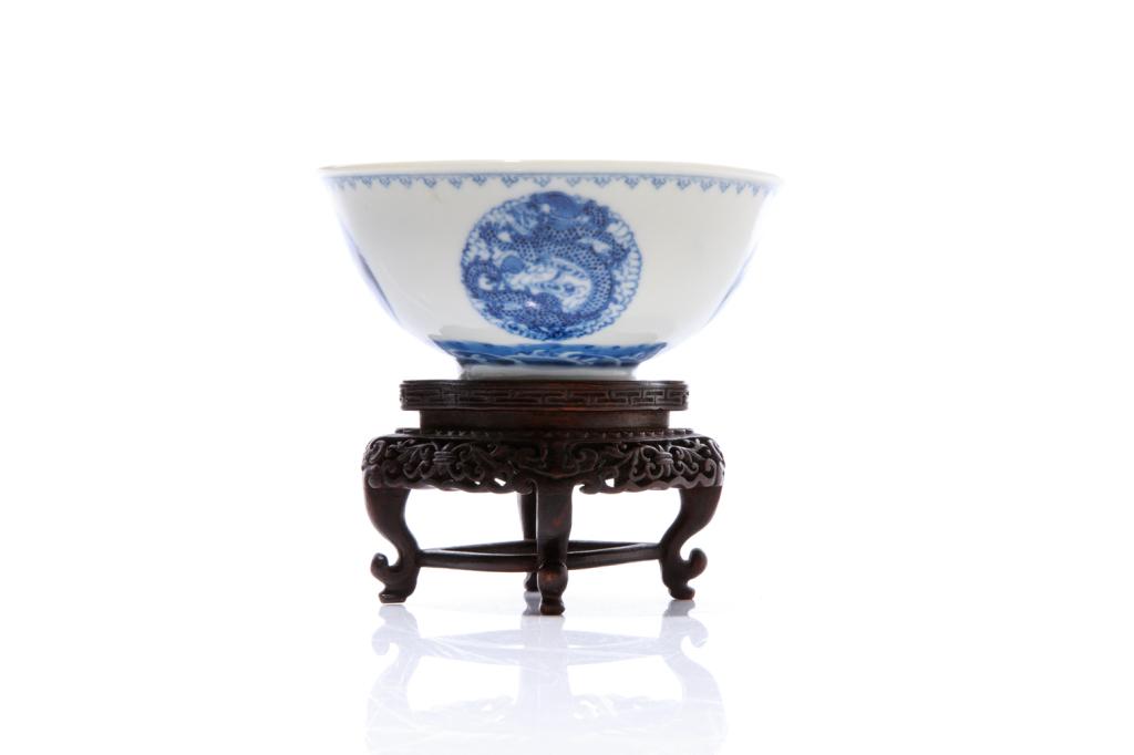 BLUE & WHITE PORCELAIN PHOENIX & DRAGON BOWL: Exterior painted with roundels of dragon and phoenix. Six character Guangxu mark to base and of the period. With a finely carved wood stand. H. of bowl: 5.5cm (2 1/8 in.) Dia. 13cm (5 in.) Provenance: