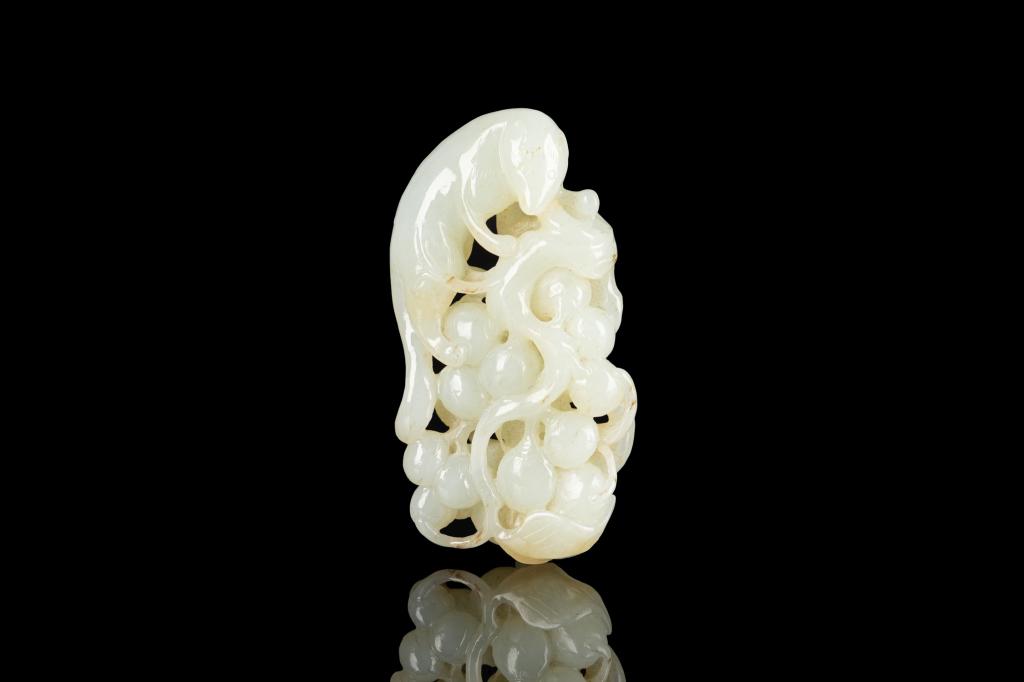 CHINESE JADE SQUIRREL AND GRAPES: Pale celadon tone with brown spot inclusions. Carving of a squirrel amongst grapes. L. 9cm (3 1/2 in.)