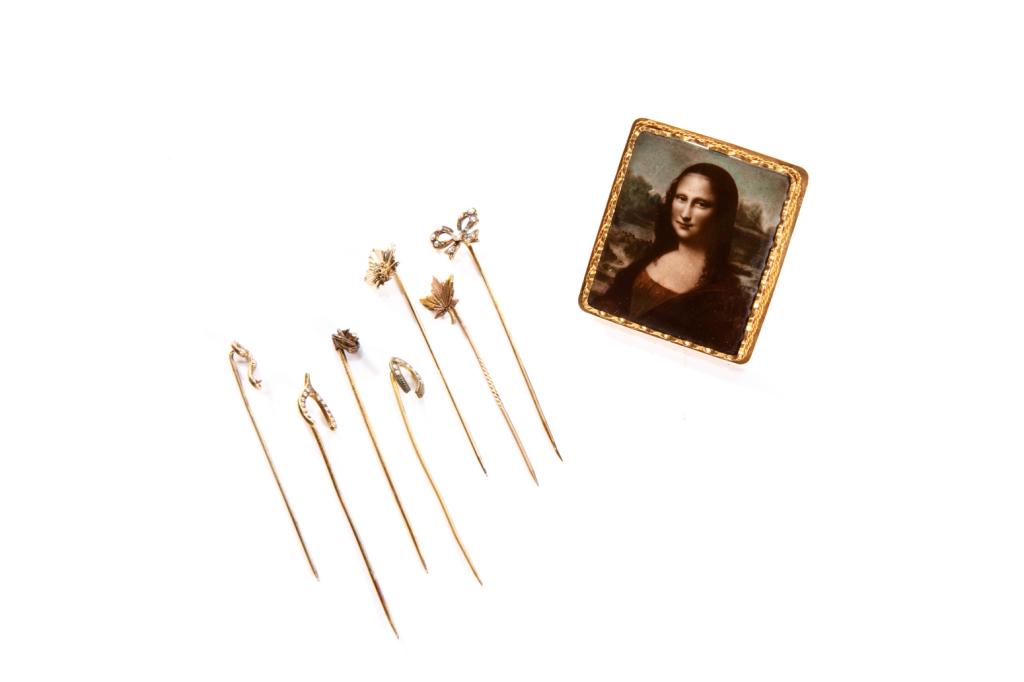 GOLD & PORCELAIN BROOCH: Enamelled porcelain print of the Mona Lisa in a yellow gold frame, testing 14k. Together with seven gold stick pins, embellished with small pearls or diamond. With case. Late 19th to early 20th C.