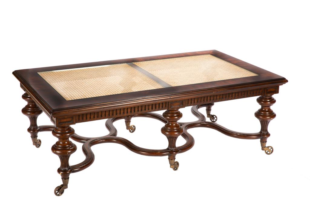 REGENCY STYLE WOOD & RATTAN COFFEE TABLE: Exaggerated oversized legs with brass casters, x-form stretcher, and glazed over rattan top. H. 20 W. 56 D. 32 in.