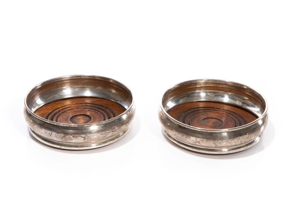 PAIR OF ENGLISH SILVER WINE COASTERS: Two modern sterling silver wine coasters with carved wood bases. Hallmarked Da-mar silverware, London, 1977. Dia. 13.5 cm (5 1/4 in.)