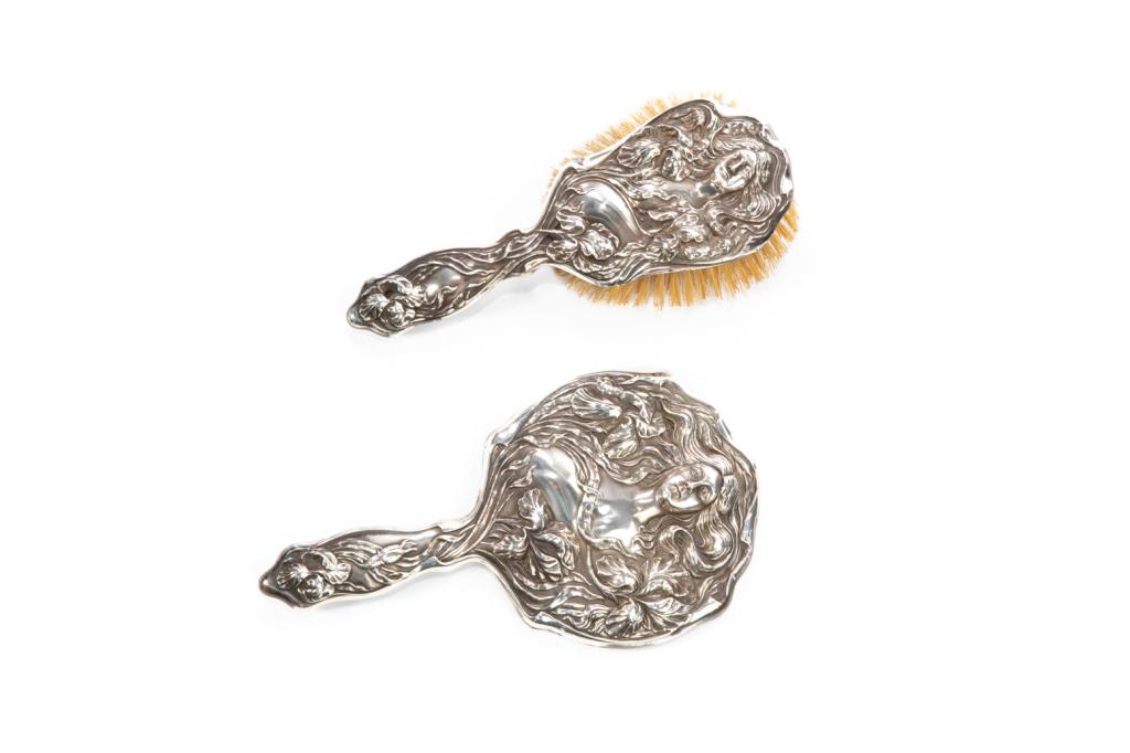 ART NOUVEAU SILVER BRUSH AND MIRROR: A turn of the century American sterling Art Nouveau hand mirror and brush.