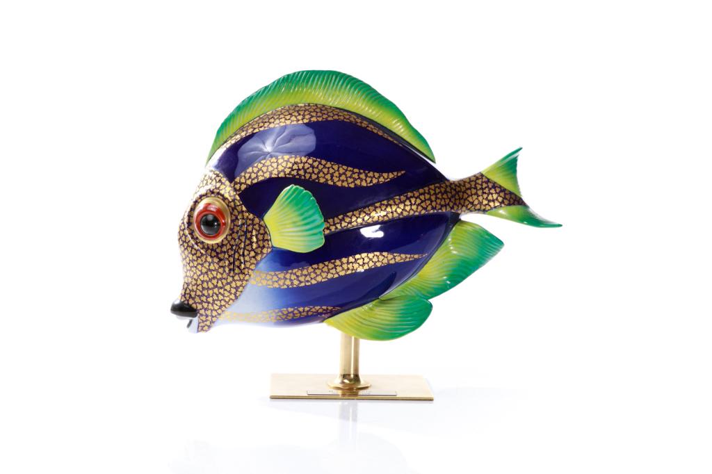 ITALIAN OGGETTI MANGANI FISH SCULPTURE: A fish figure in cobalt blue with gilded accents, as well as green and yellow fins. Fish is mounted on a gilded rectangular base with a label to the underside "Made in Italy." Comes in a large fitted