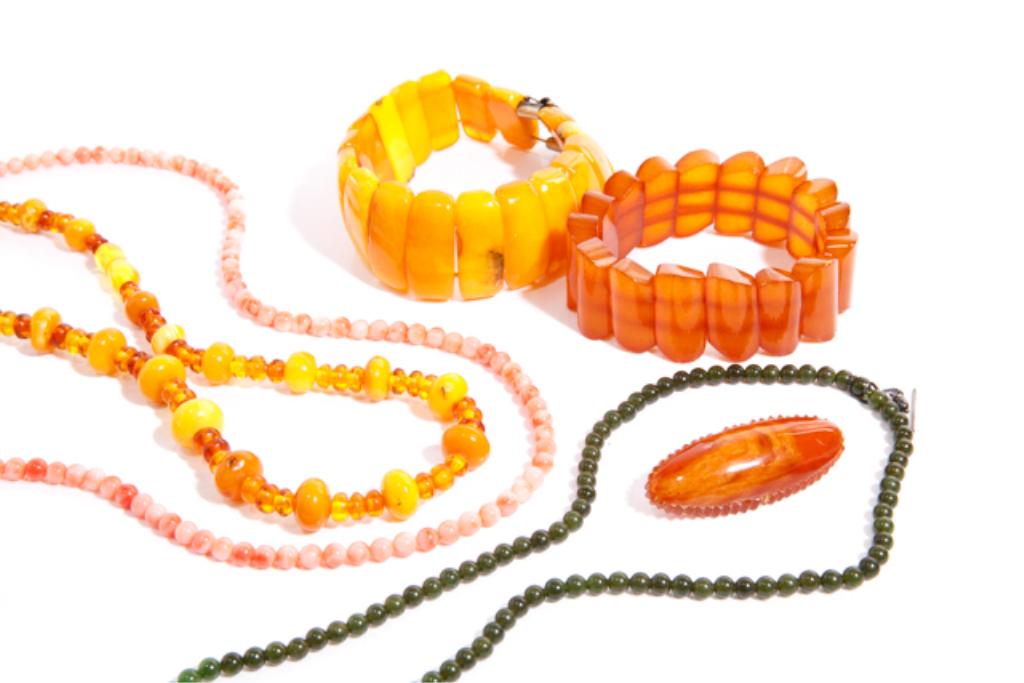 AMBER, CORAL, & JADE JEWELLERY: Including one coral, one amber, and one nephrite beaded necklace. Two amber link bracelets and one amber brooch. Bidders living outside of Canada are warned to proceed with care before bidding on this