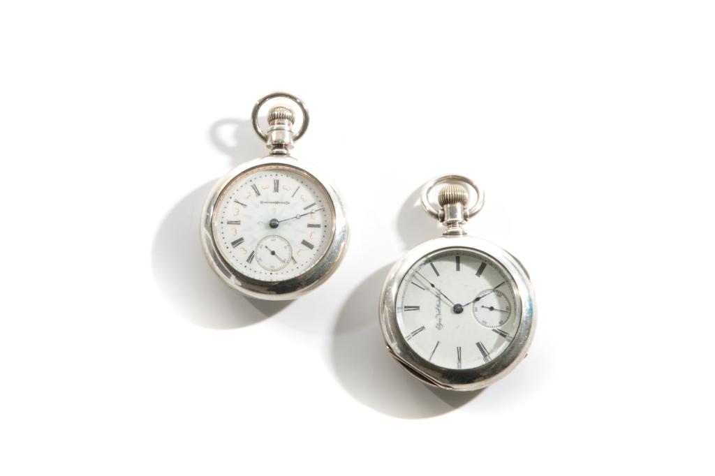 TWO SILVER MENS' POCKET WATCHES: Two open face silver pocket watches. One by Elgin National Watch Co. case opens both face and back. Interior back marked "Dueber Coin" with an anchor logo. Serial number 257075. One by Hampden WatonCo