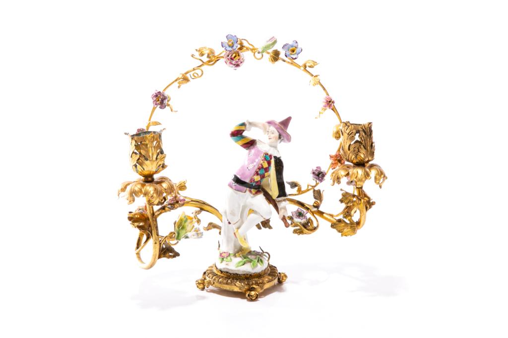 MEISSEN HARLEQUIN FIGURAL TWO LIGHT CANDELABRA: Hand painted, mounted on a gilt pressed metal table candelabra with applied porcelain flowers surrounding. H. 24 cm (9 1/2 in.)