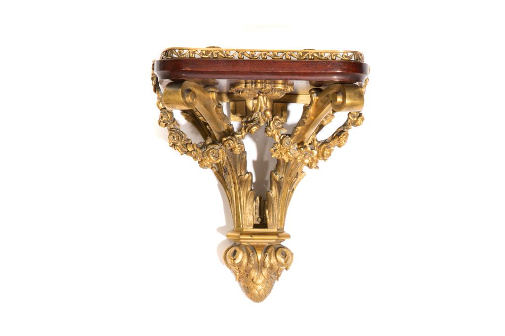 SMALL GILT BRONZE WALL CLOCK BRACKET: Mahogany platform with ormolu gallery and Rococo style support including a pineapple terminal and swags of rosettes. Marked "MP" on reverse. French, 19th C. H. 8 1/2" (21.5 cm) W. 7 1/2" (19 cm) D. 5 