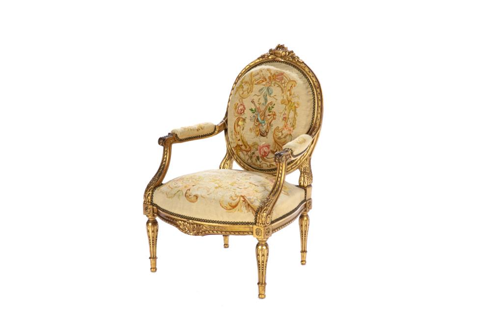 19TH C FRENCH CARVED GILTWOOD FAUTEUIL: The armchair with rounded back and tapering reeded legs in the Louis XIV manner, petite point upholstery. H. 39" W. 26" D. 28"