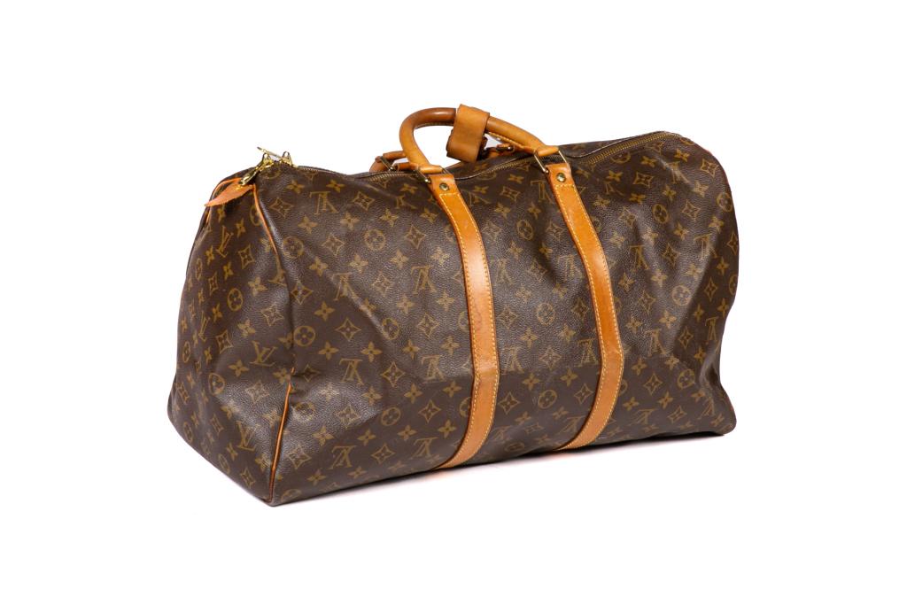 LOUIS VUITTON MONOGRAM KEEPALL DUFFEL BAG: Brown and tan monogram coated canvas Keepall 50 duffel bag with brass hardware, dual flat top handles, tan Vachetta leather trim, brown canvas lining and two-way zip closure at top. With luggage tag. 