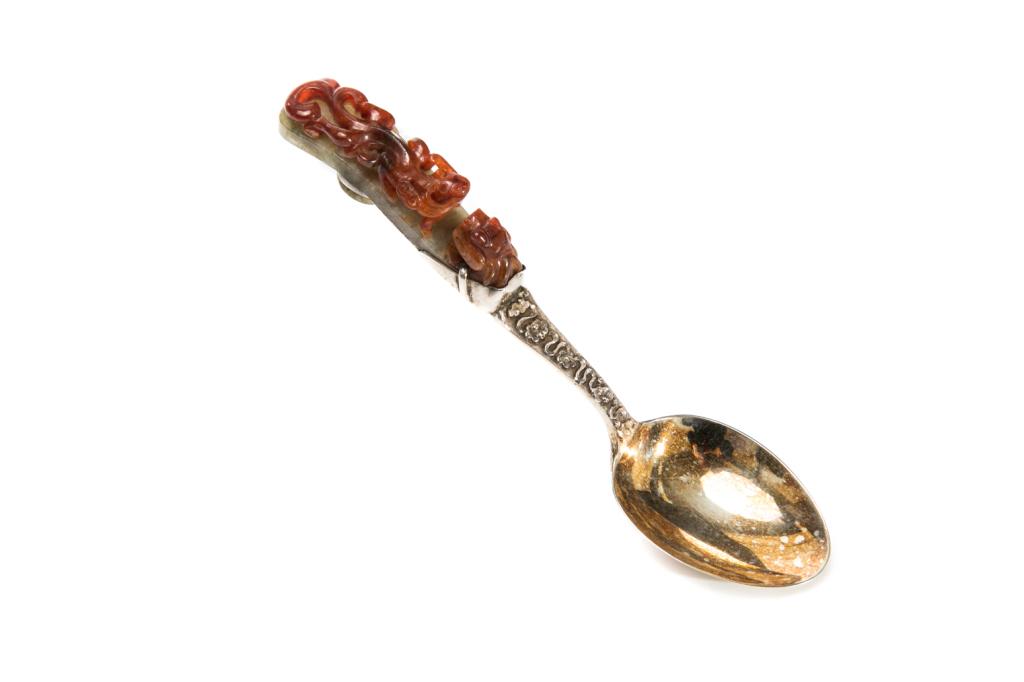 SILVER SPOON WITH JADEITE DRAGON HOOK HANDLE: Two-toned jadeite with celadon and red, carved as a father and song dragon duo. Jadeite length: 7.5cm (3 in.) Overall length: 19cm (7 1/2 in.)