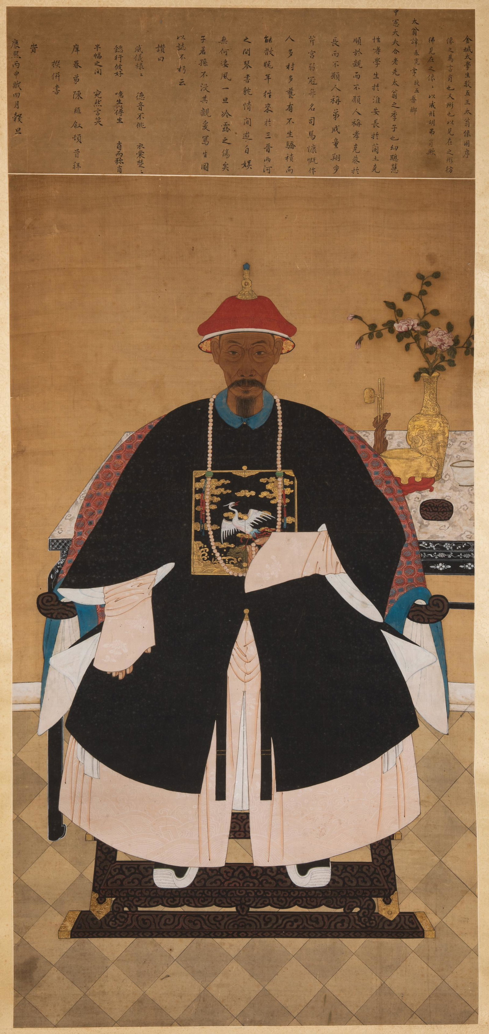 CHINESE ANCESTOR PORTRAIT SCROLL: Painted with a Qing dynasty official figure dressed in a formal robe with rank badge, seated in front of a table displaying scholarly items. Calligraphy inscription to top. Ink and colour onsilk, moun