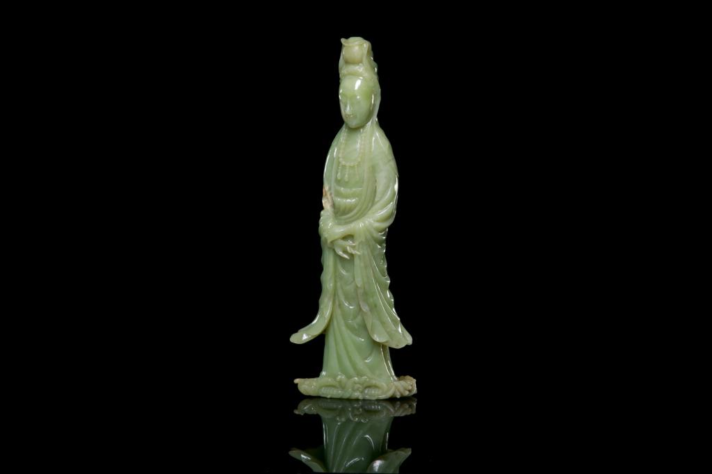 CHINESE CELADON JADE CARVED GUANYIN FIGURE: The standing Guanyin standing on waves, dressed in elongated robes. H. 34cm (13 1/2 in.)