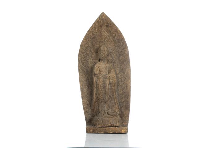 CHINESE NORTHERN WEI STYLE STONE BUDDHA STELE: Carved with a standing Buddha with hands held open in abhaya (absence of fear) and varada (charity) mudras, against a large flaming mandorla with a pointed top, and standing on a lotus pedestal. H. 53