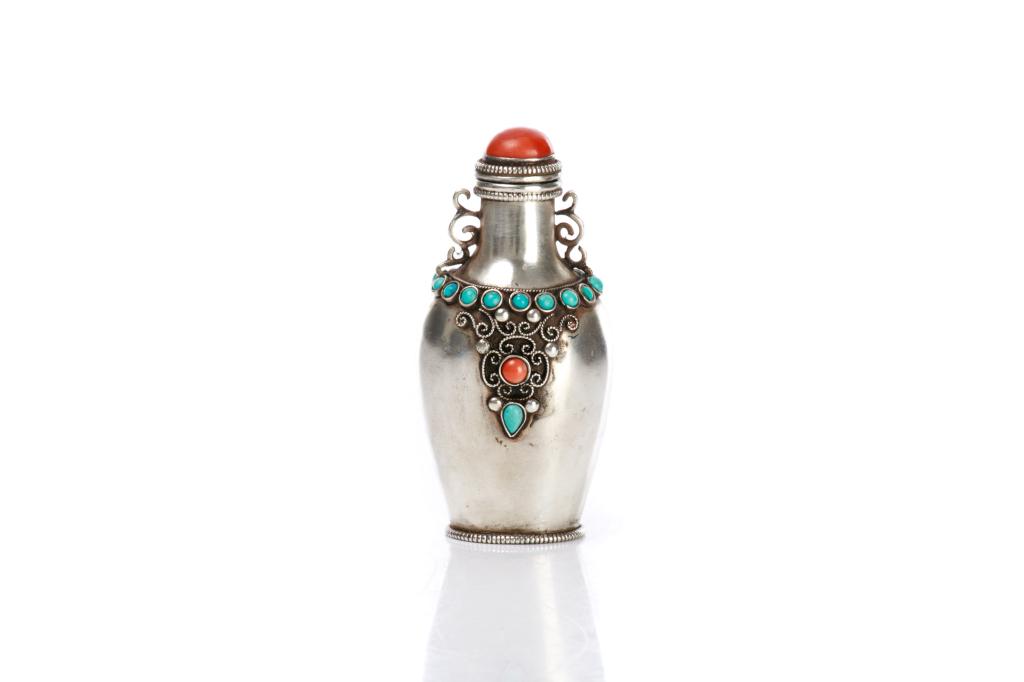 TIBETAN OR MONGOLIAN SILVER SNUFF BOTTLE: Inlaid with turquoise and coral cabochon, and cover with coral. H. 8cm (3 1/8 in.) Bidders living outside of Canada are warned to proceed with care before bidding on this lot as it cannot be shipped o