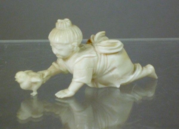 JAPANESE IVORY OKIMONO OF A BOY AND CHICK, MEIJI: Japanese ivory okimono of boy crawling holding a chick. 19th century. L 6.4 cm (2 1/2 in).Provenance: The Estate of Mr. John Henry Stuart Gooderham, Toronto.