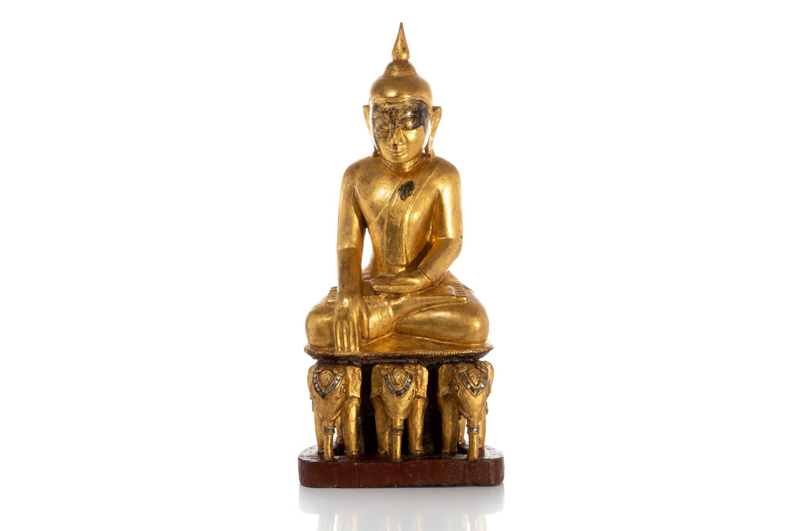 BURMESE GILT LACQUERED WOOD SEATED BUDDHA: Burmese, probably 17th century. In the bhumisparsa mudra (calling earth to witness enlightenment) posture, seated on three elephants decorated with inset glass and mirrors. 64 x 27 x 15.5 cm (25 x 10.