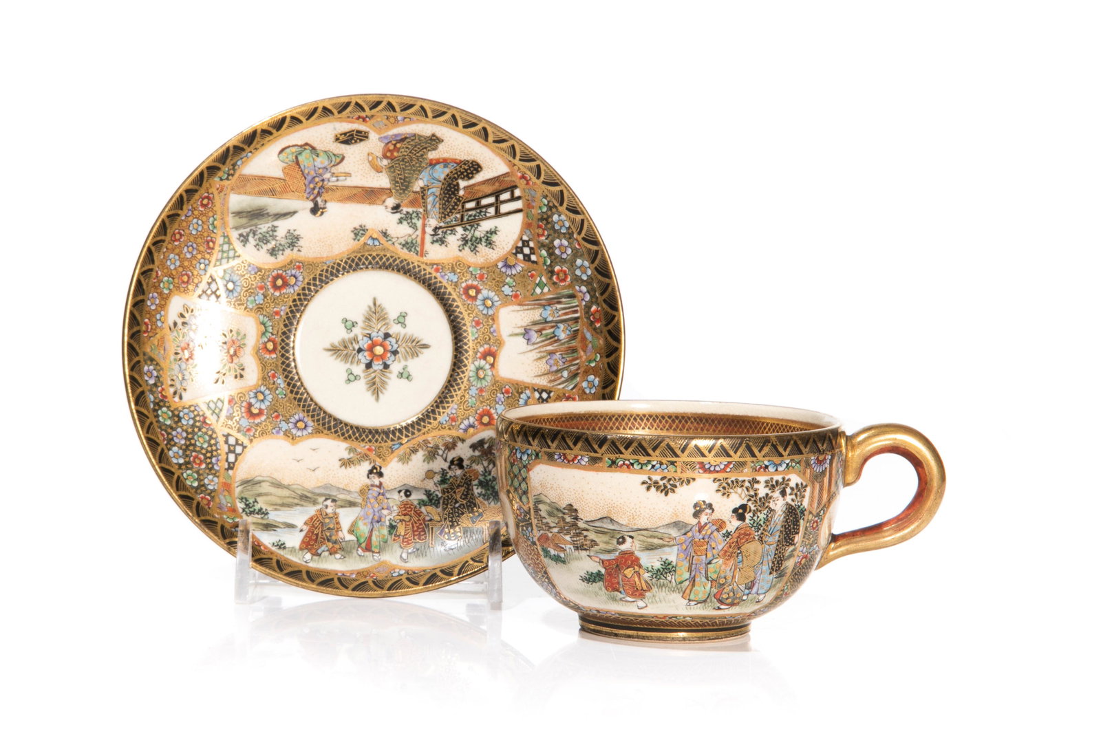 JAPANESE SATSUMA CUP AND SAUCER: Meiji period, featuring asymmetrical panels alternating with figures and flowers, the cup having similar painted decoration on the exterior, with flowers on the interior of the classic cream coloured 
